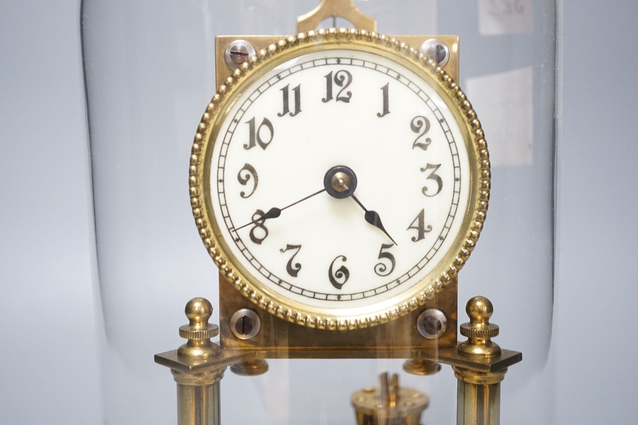 An early 20th century month going mantel timepiece, with a silk suspension, under a glass dome 29cm